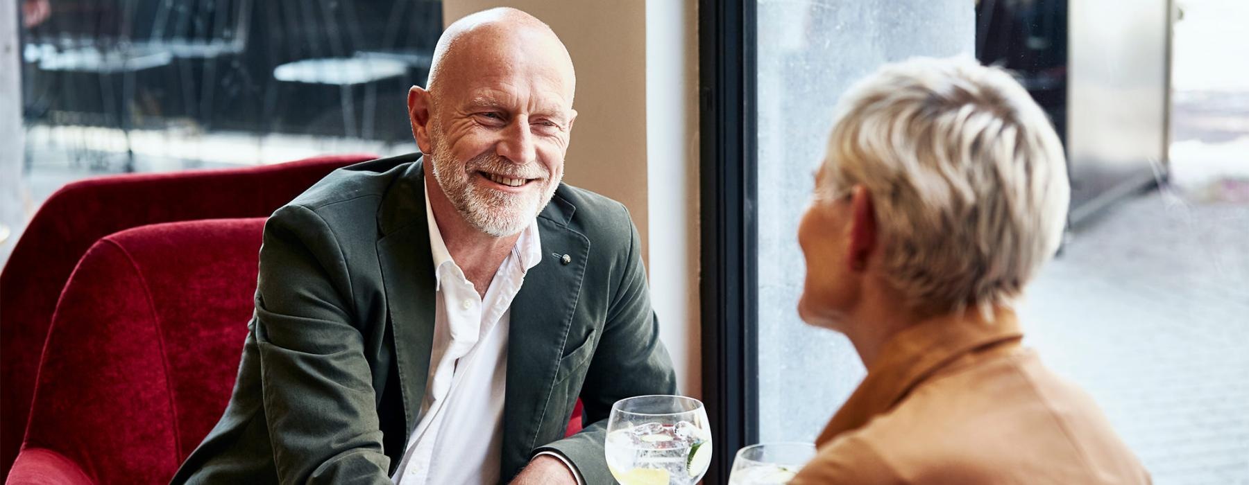 a man and a woman sitting at a table with cocktails