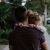 tired little girl rests her head on her father's shoulder as he carries her down the city sidewalk